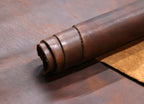 Rolled-up piece of brown leather on a textured surface