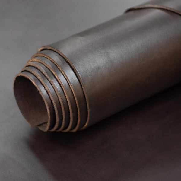 Rolled-up brown leather sheet on a dark gray background
