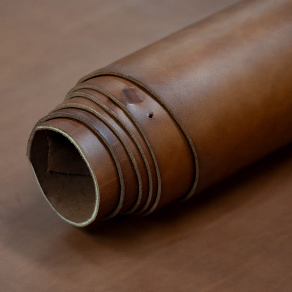 Roll of brown leather on a wooden surface