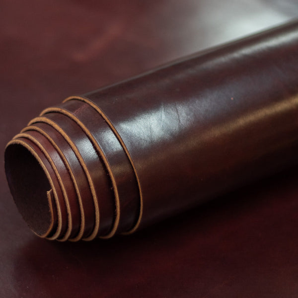 Close-up of a roll of brown leather with visible stitching on a dark surface.